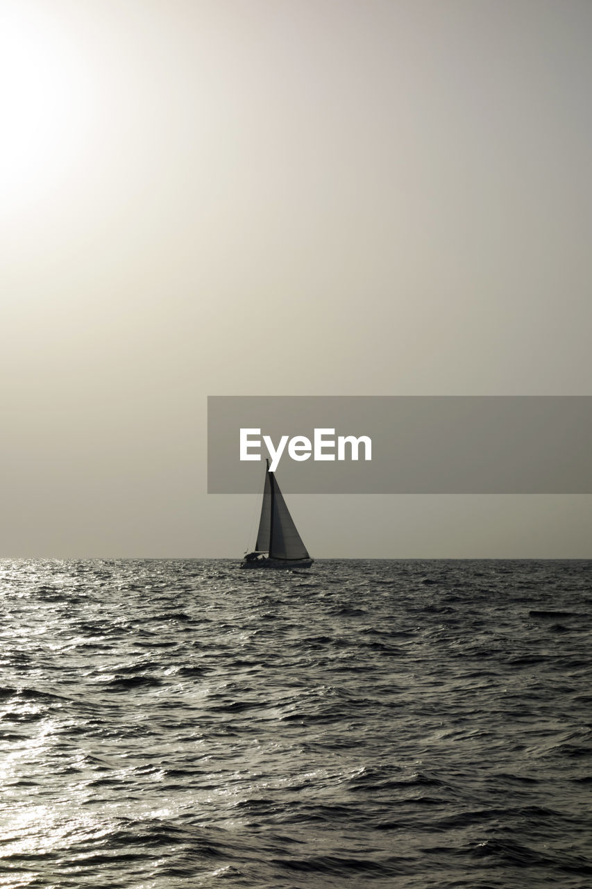 Sailboat sailing in calm sea against clear sky