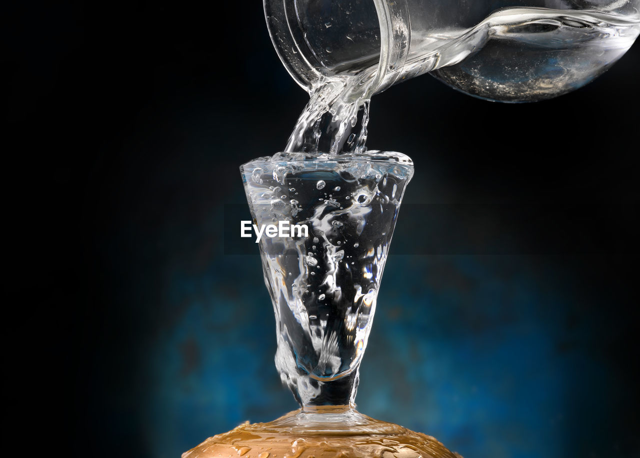 CLOSE-UP OF GLASS POURING WATER