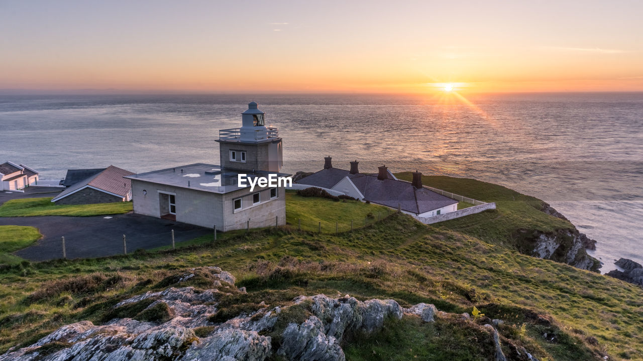 SCENIC VIEW OF SEA AGAINST BUILDINGS DURING SUNSET