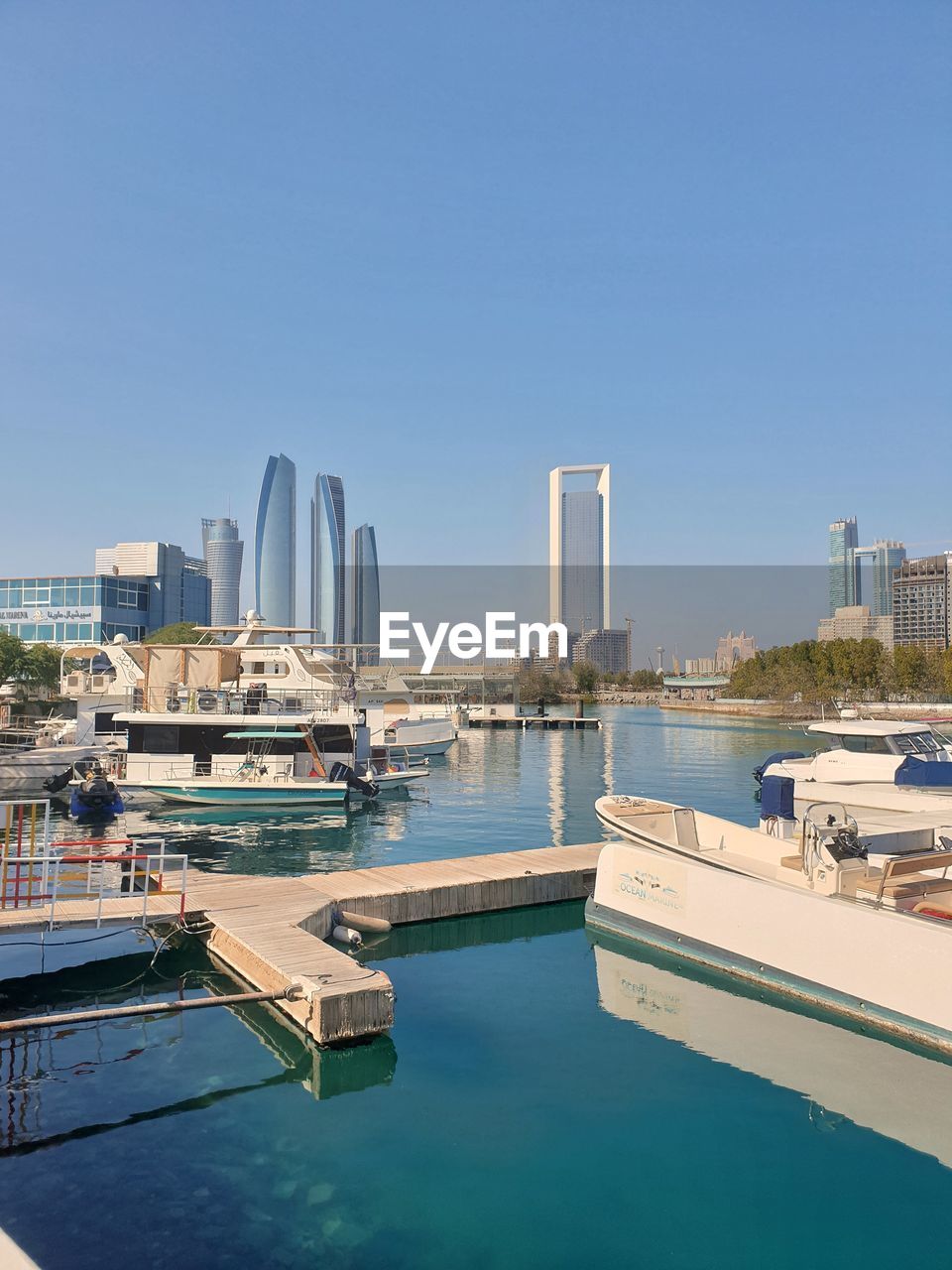 View of boats in harbor against clear sky with towers in the background 