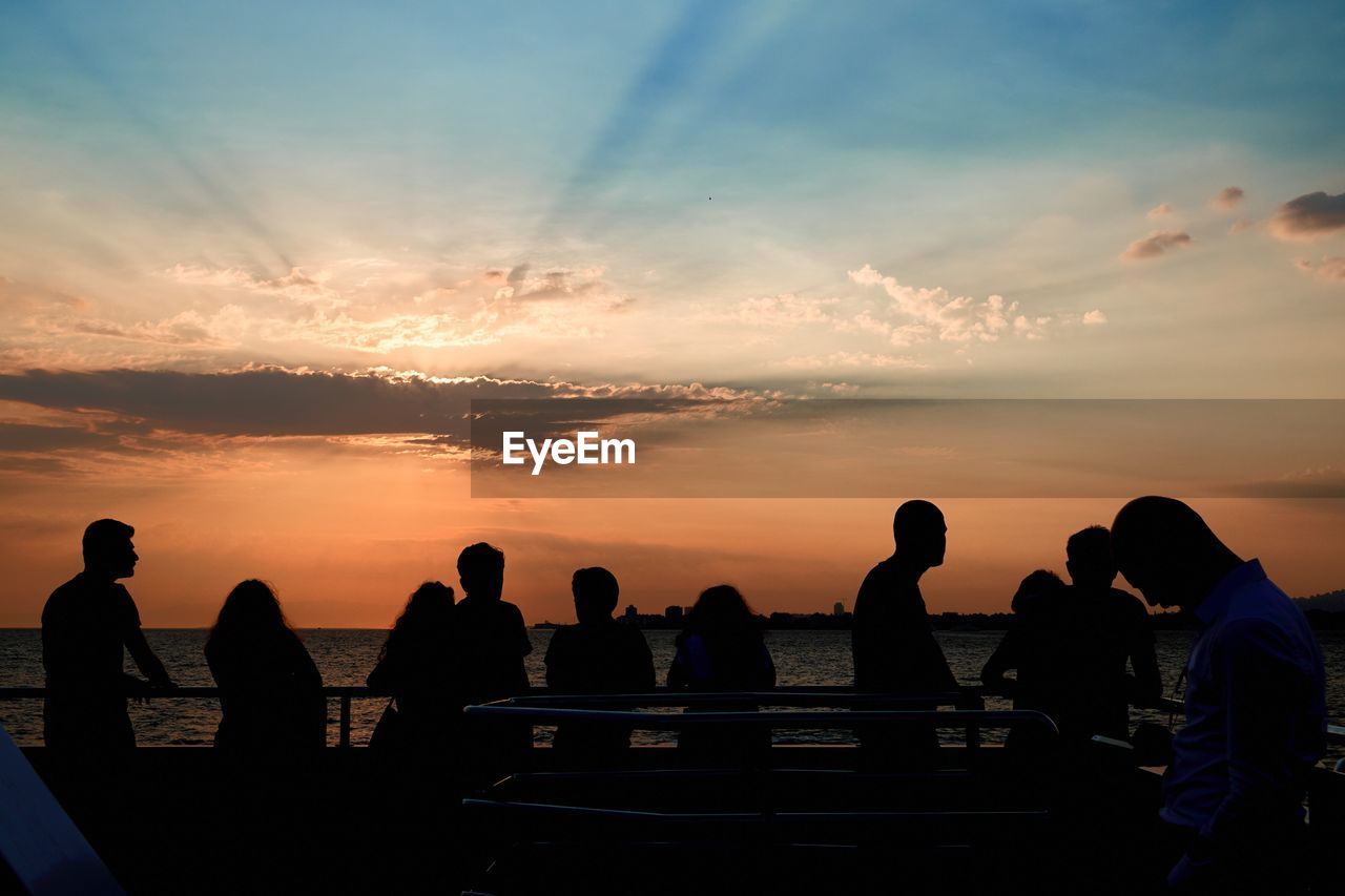 SILHOUETTE PEOPLE AGAINST SEA DURING SUNSET