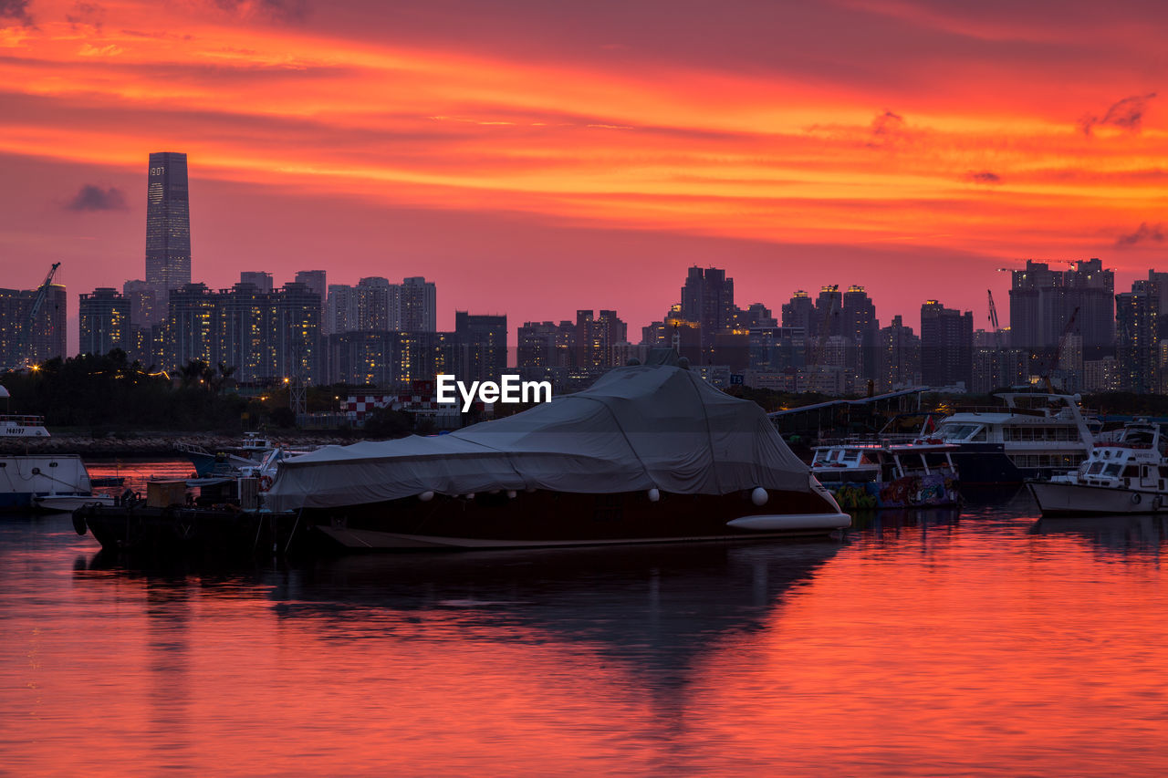 Scenic view of river and buildings against orange sky