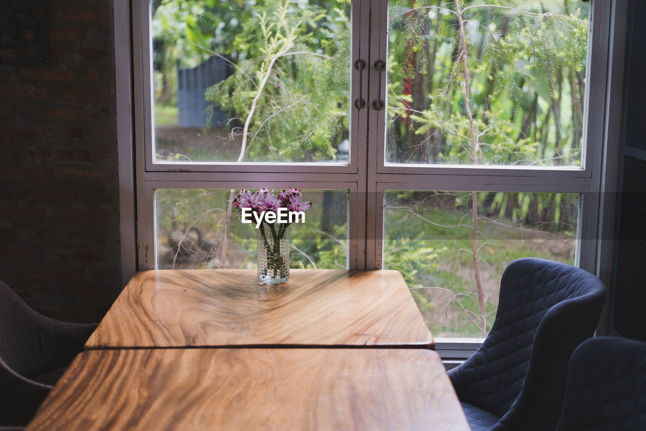 FLOWER VASE ON TABLE BY WINDOW