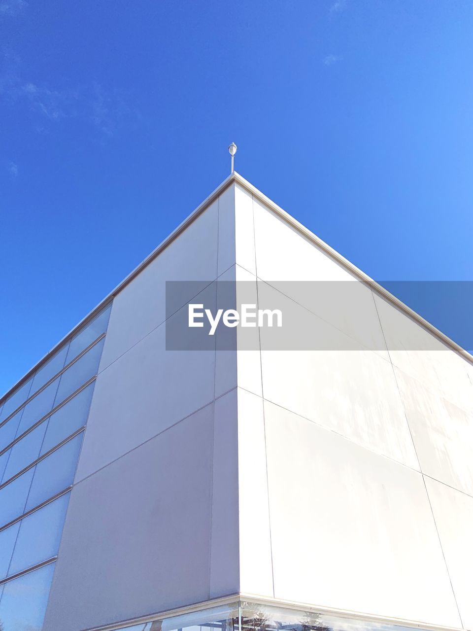 LOW ANGLE VIEW OF GLASS BUILDING AGAINST CLEAR BLUE SKY