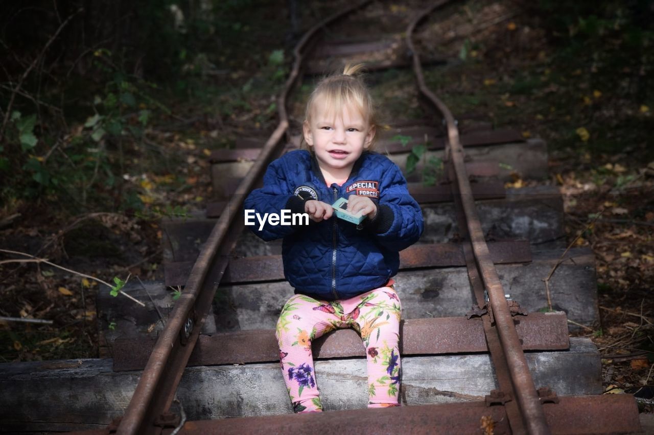 High angle view of cute baby girl sitting on railroad track