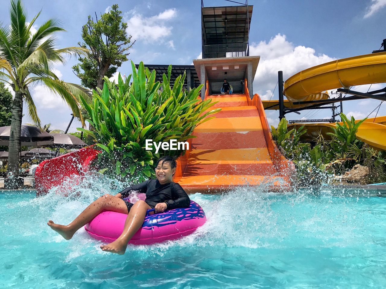 PEOPLE ENJOYING IN SWIMMING POOL AGAINST BUILDINGS