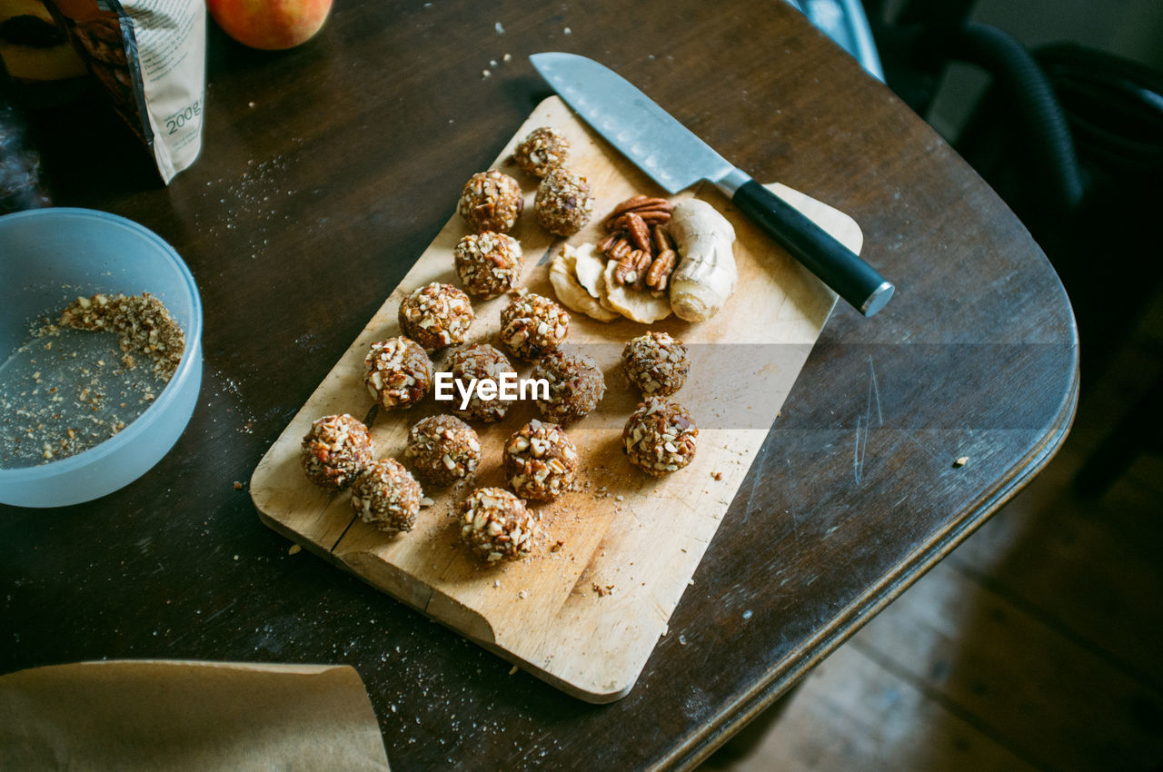 High angle view of almond balls with knife on cutting board over table