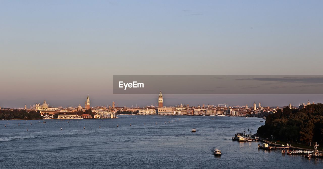 River and buildings against clear sky during sunset