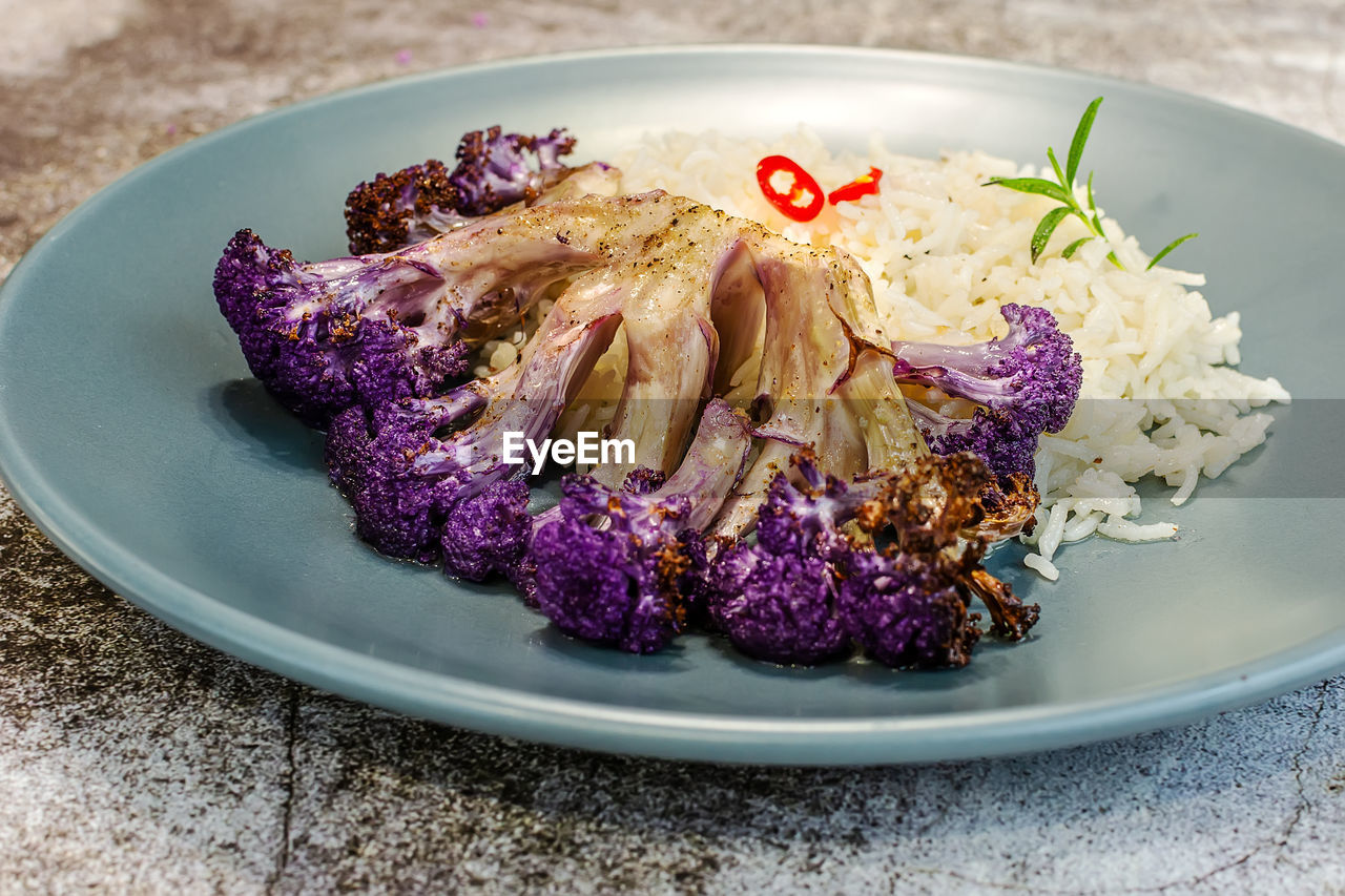 Purple cauliflower in a white baking dish in the oven