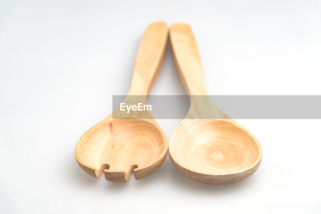 Close-up of wooden spoon and spork over white background