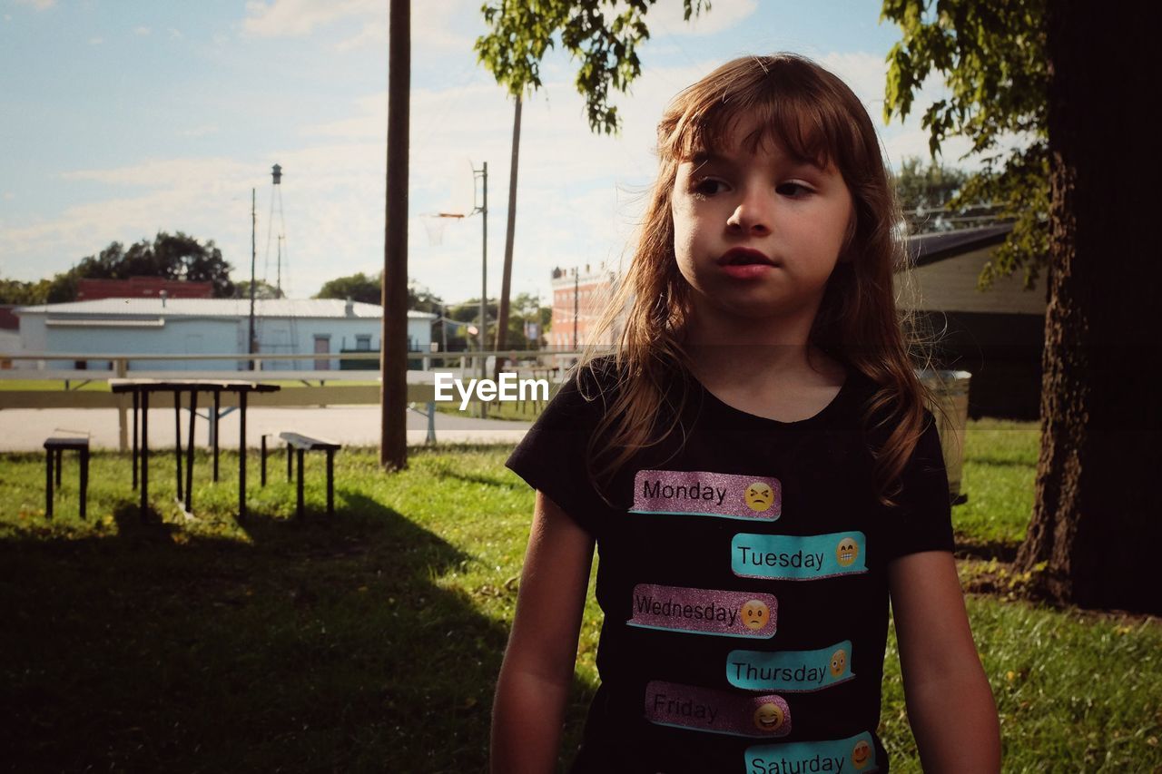 Cute girl looking away while standing in park