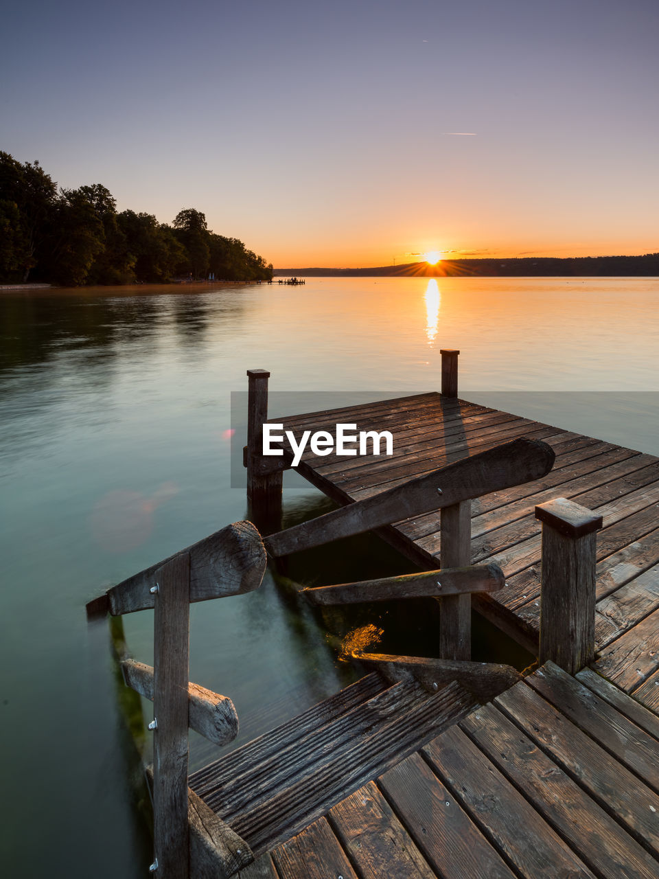 WOODEN JETTY ON LAKE AGAINST SKY DURING SUNSET