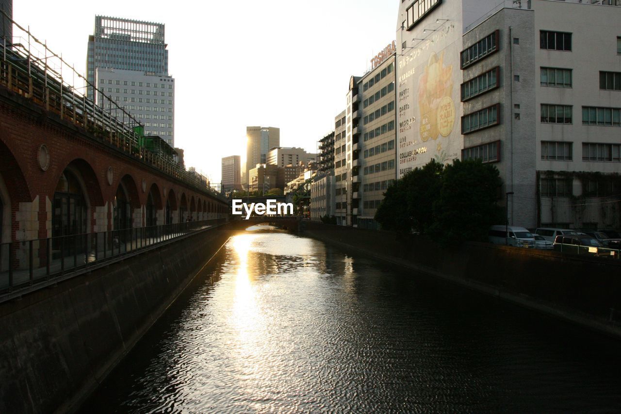 Bridge by river in city against sky