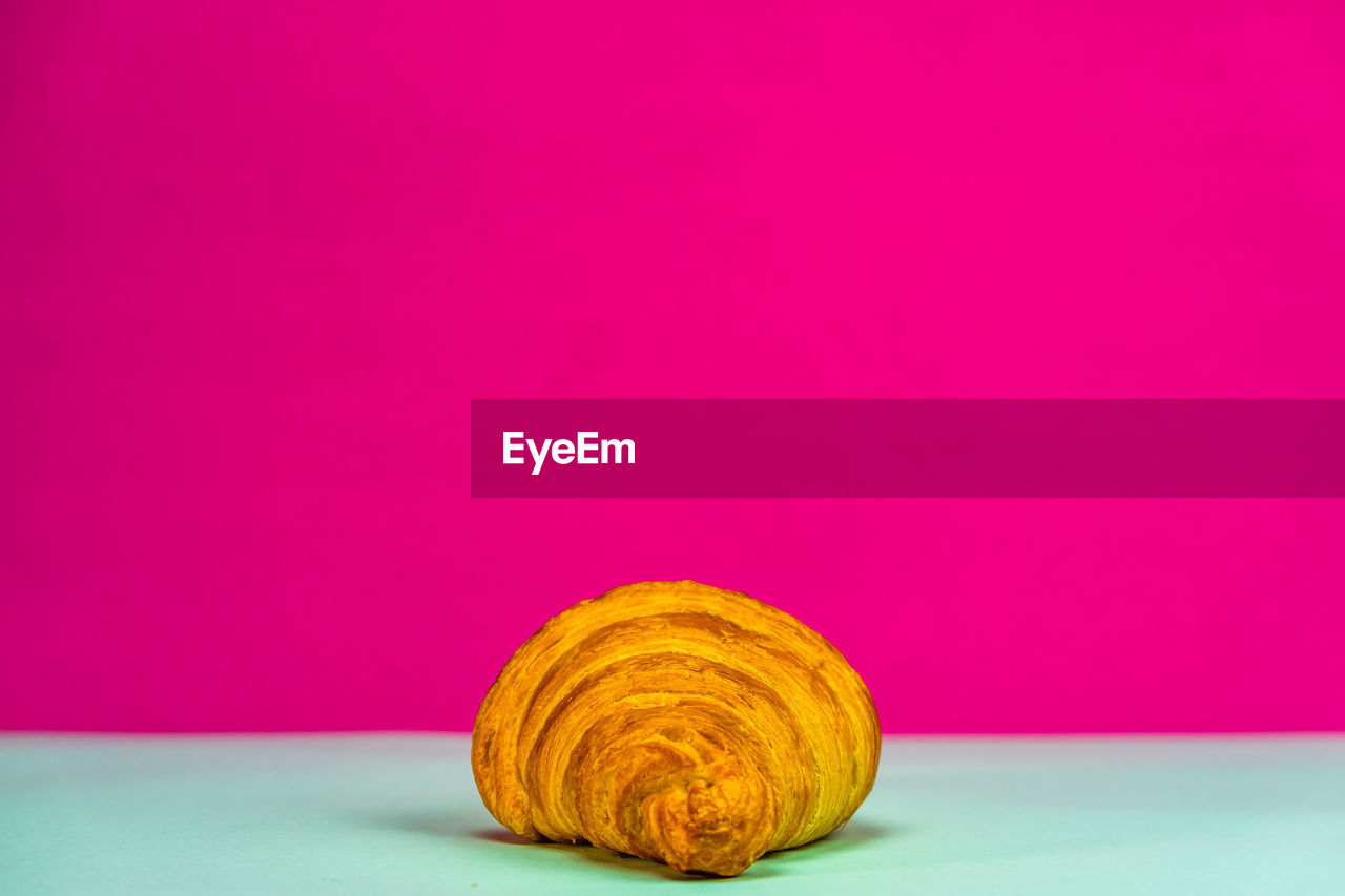 CLOSE-UP OF BREAD ON PINK BACKGROUND