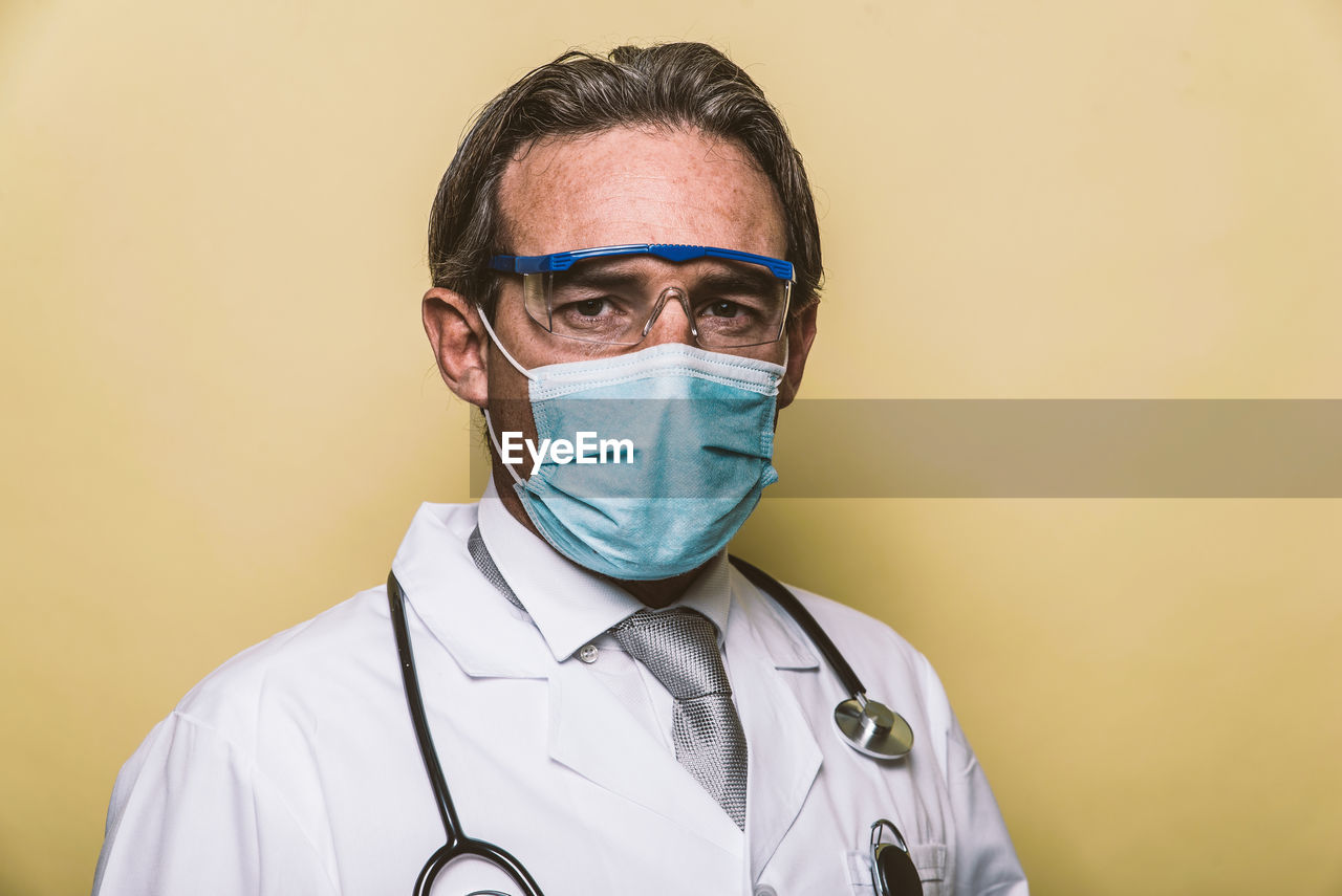 Portrait of doctor wearing mask against colored background