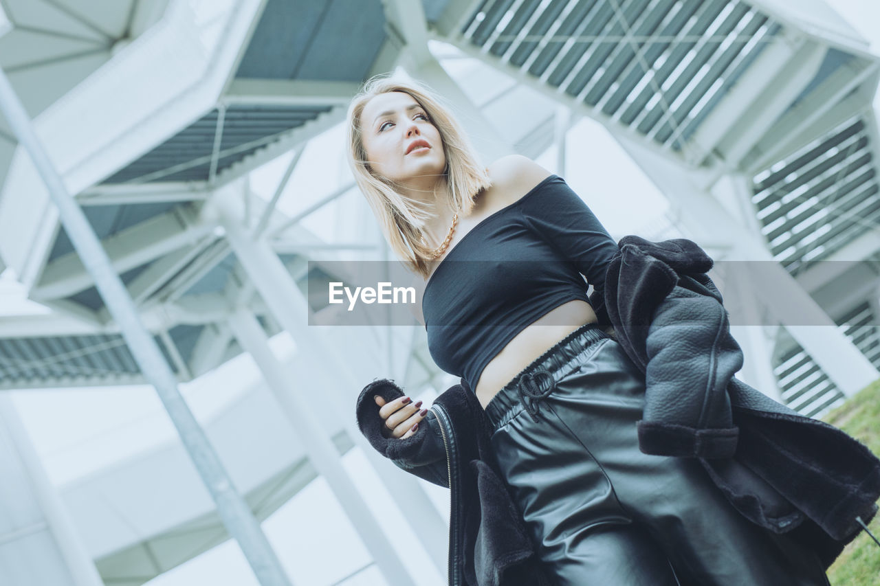 Low angle view of young woman standing in office building