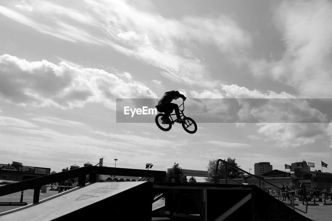 Low angle view of man performing stunt with bicycle in park against sky