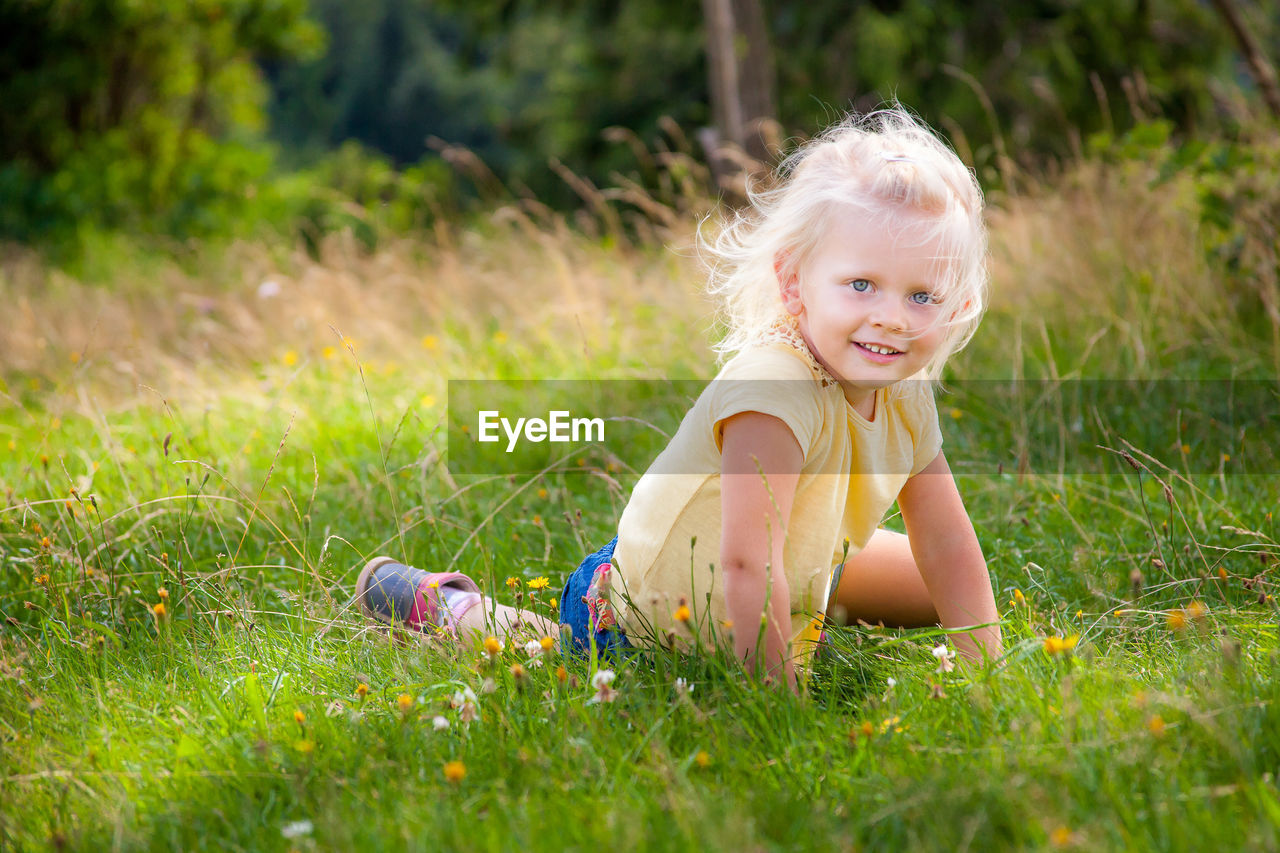 Portrait of cute girl lying on grassy field