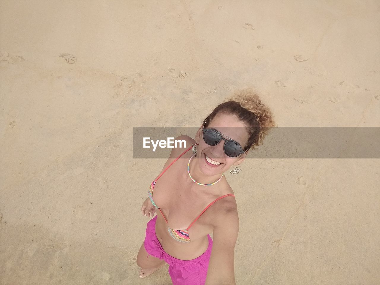 Portrait of woman wearing sunglasses standing on beach