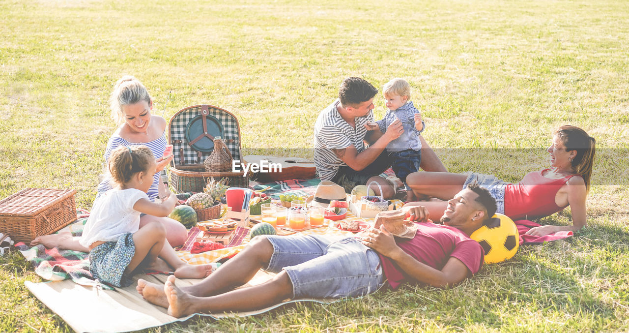 GROUP OF PEOPLE SITTING ON GRASS