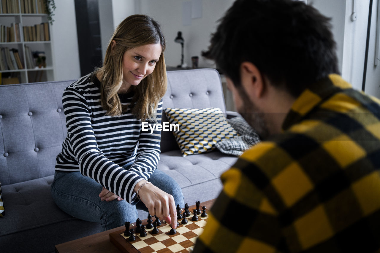 Woman and man playing chess at home