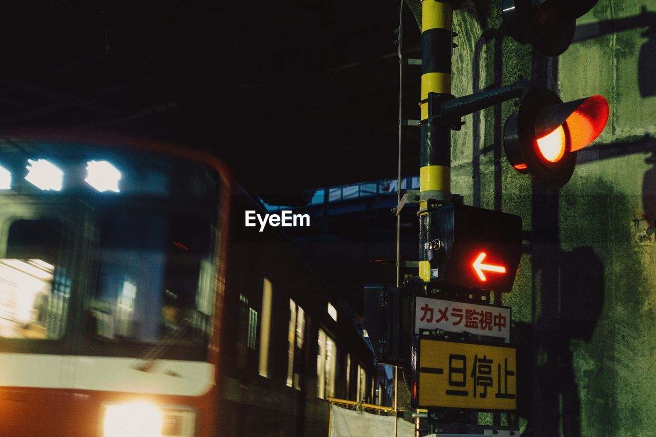 ILLUMINATED ROAD SIGN AT NIGHT IN CITY