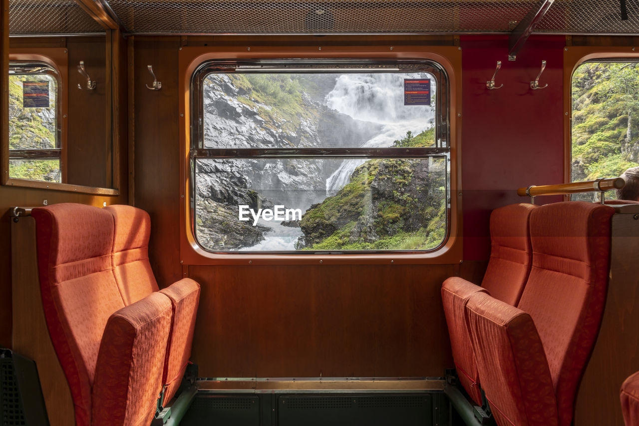 View from a railway carriage with its luxurious seats to a waterfall outside the window