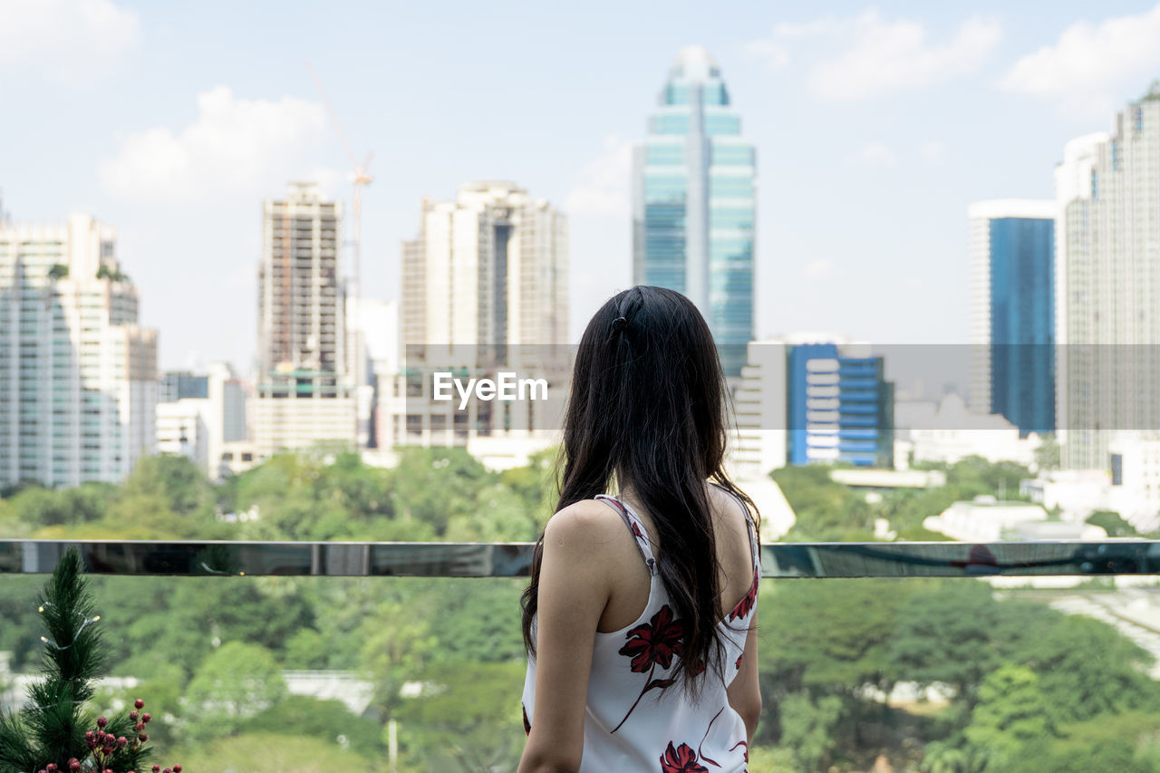 Woman standing against modern buildings in city