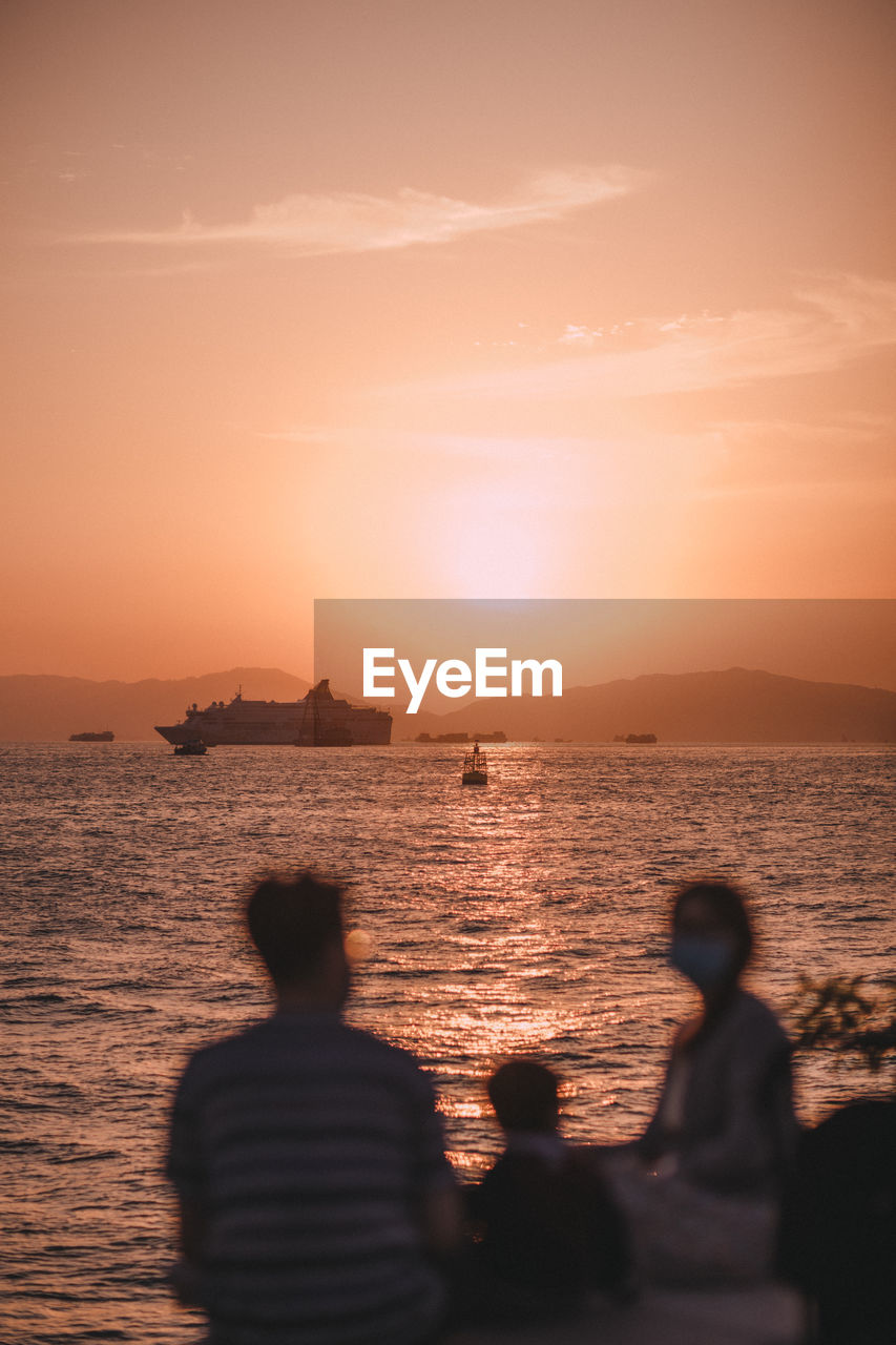 Rear view of silhouette people against sea during sunset