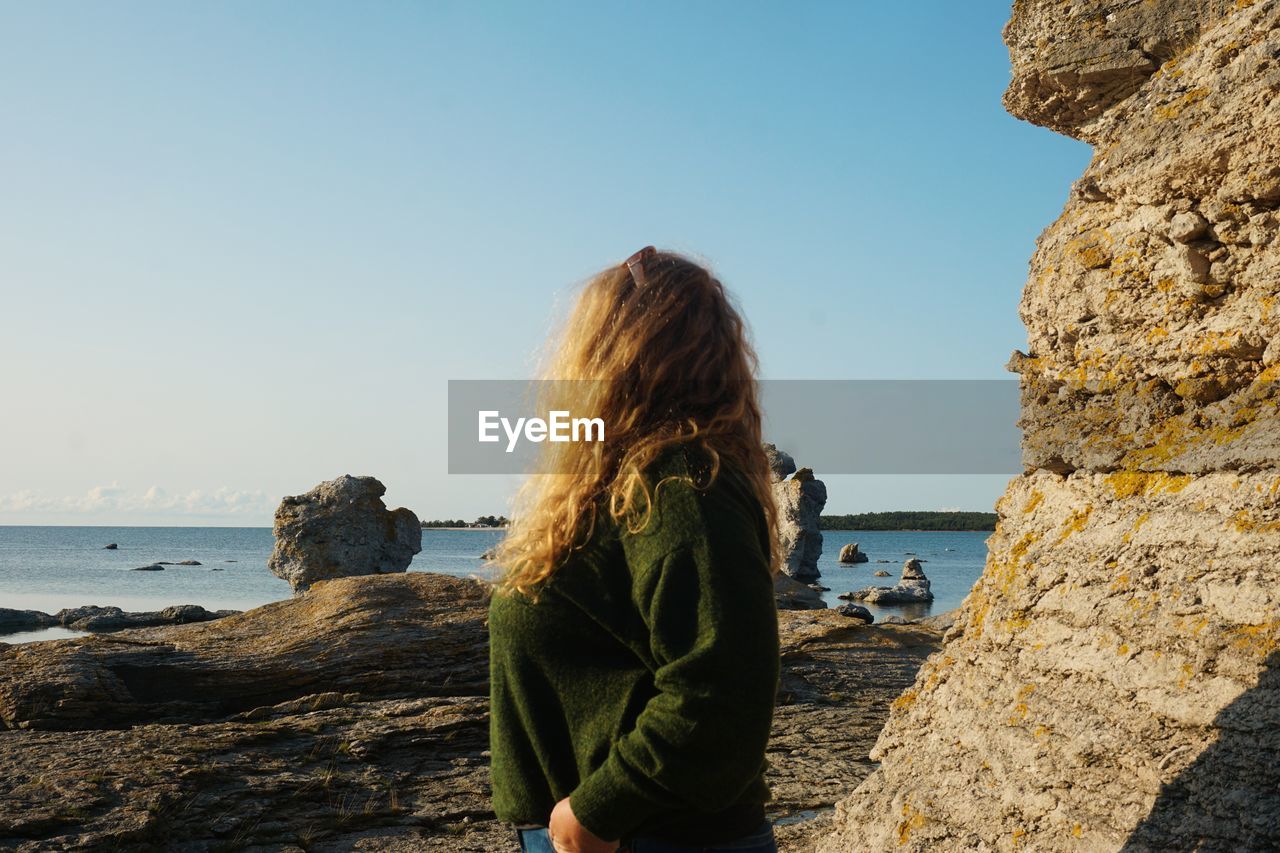 Side view of woman looking at sea against sky