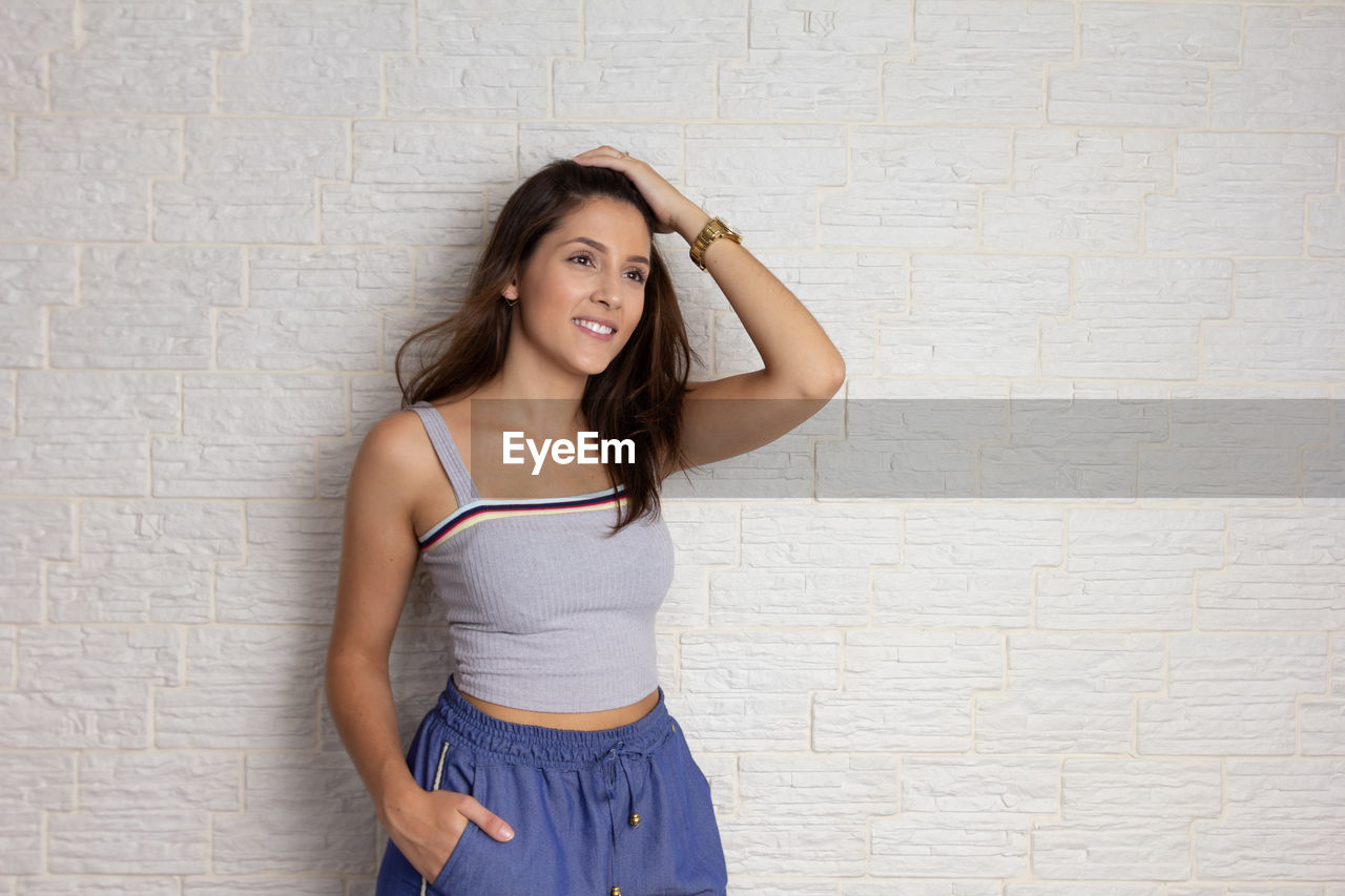 PORTRAIT OF BEAUTIFUL WOMAN STANDING AGAINST WALL