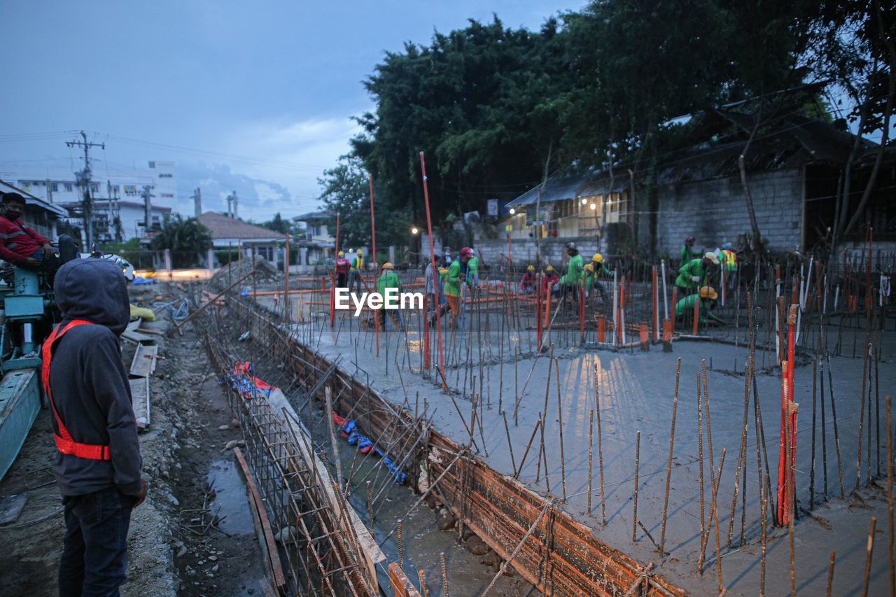 REAR VIEW OF PEOPLE ON WET STREET IN RAINY SEASON