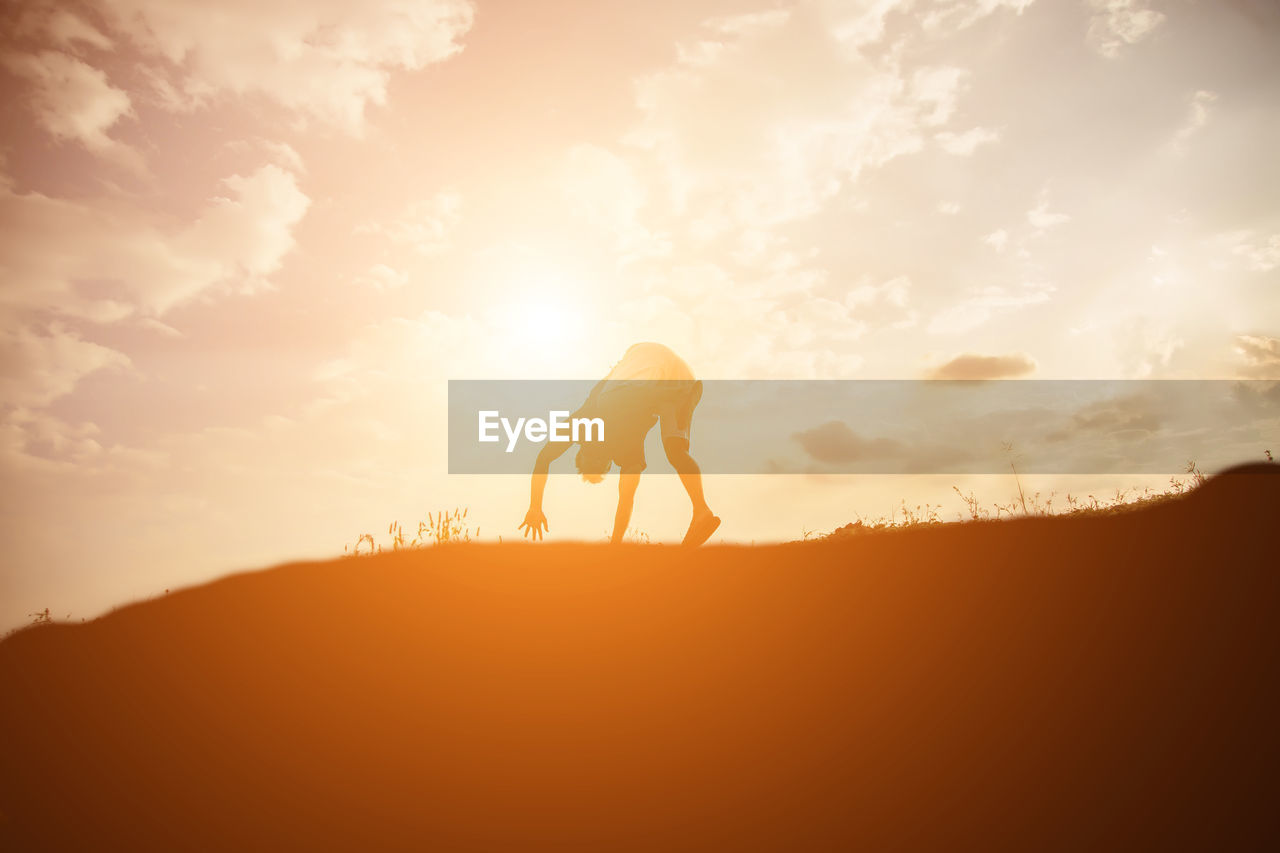 Low angle view of man on mountain against sky during sunset