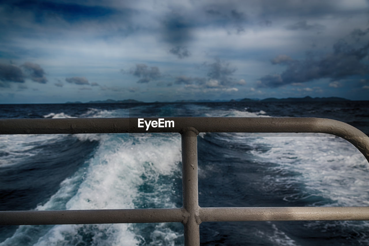 Scenic view of sea seen through railing of boat against sky 