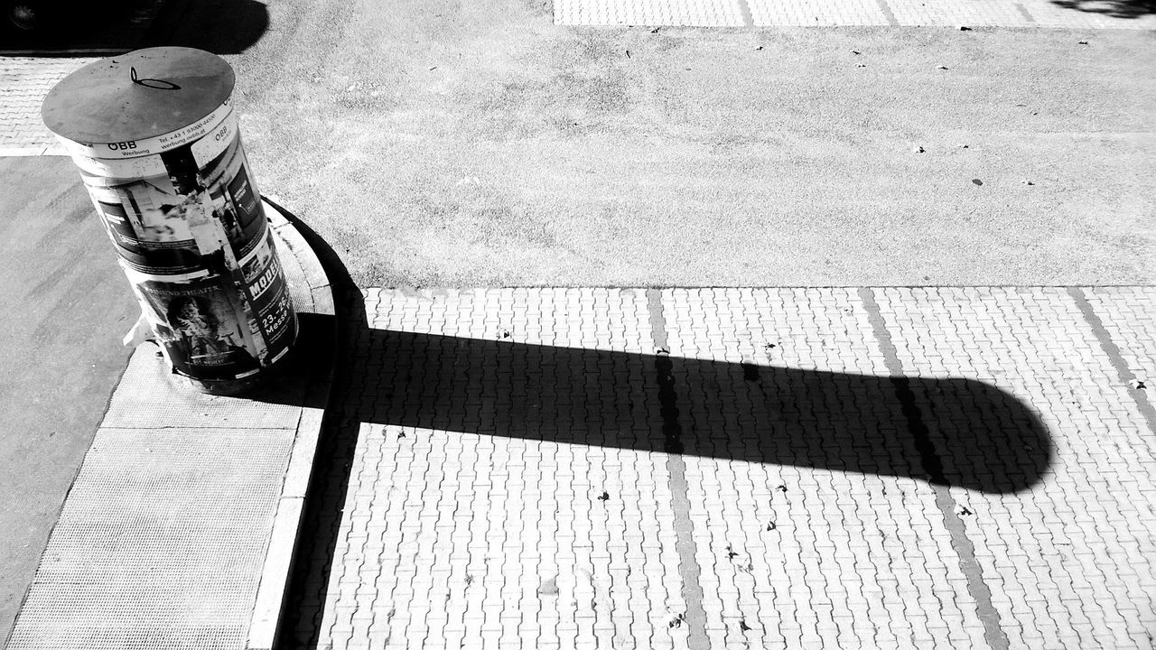 Garbage bin with shadow on road