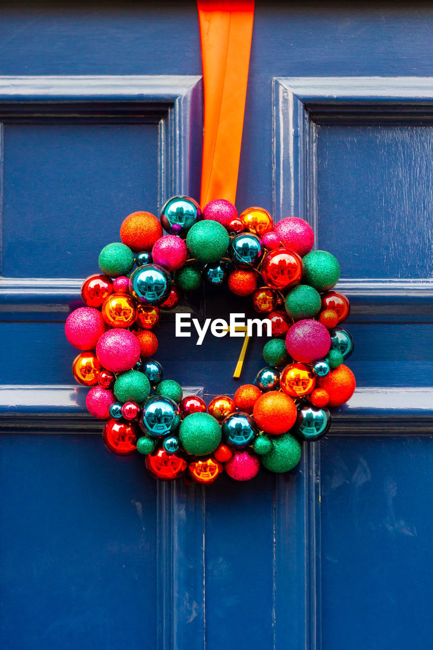 Christmas wreath consisting of colorful glass baubles on blue front door number 7 in london 