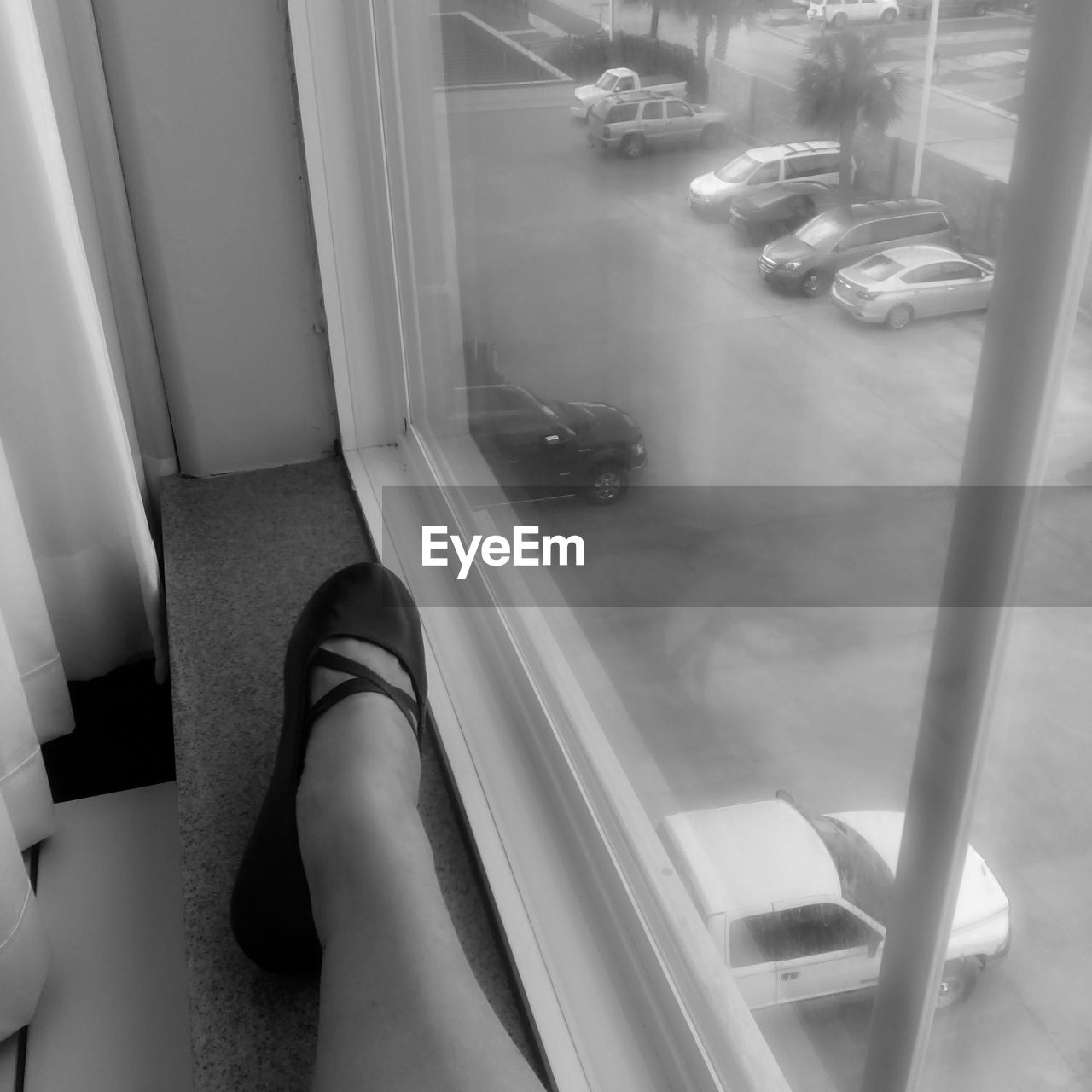 Low section of woman sitting on window