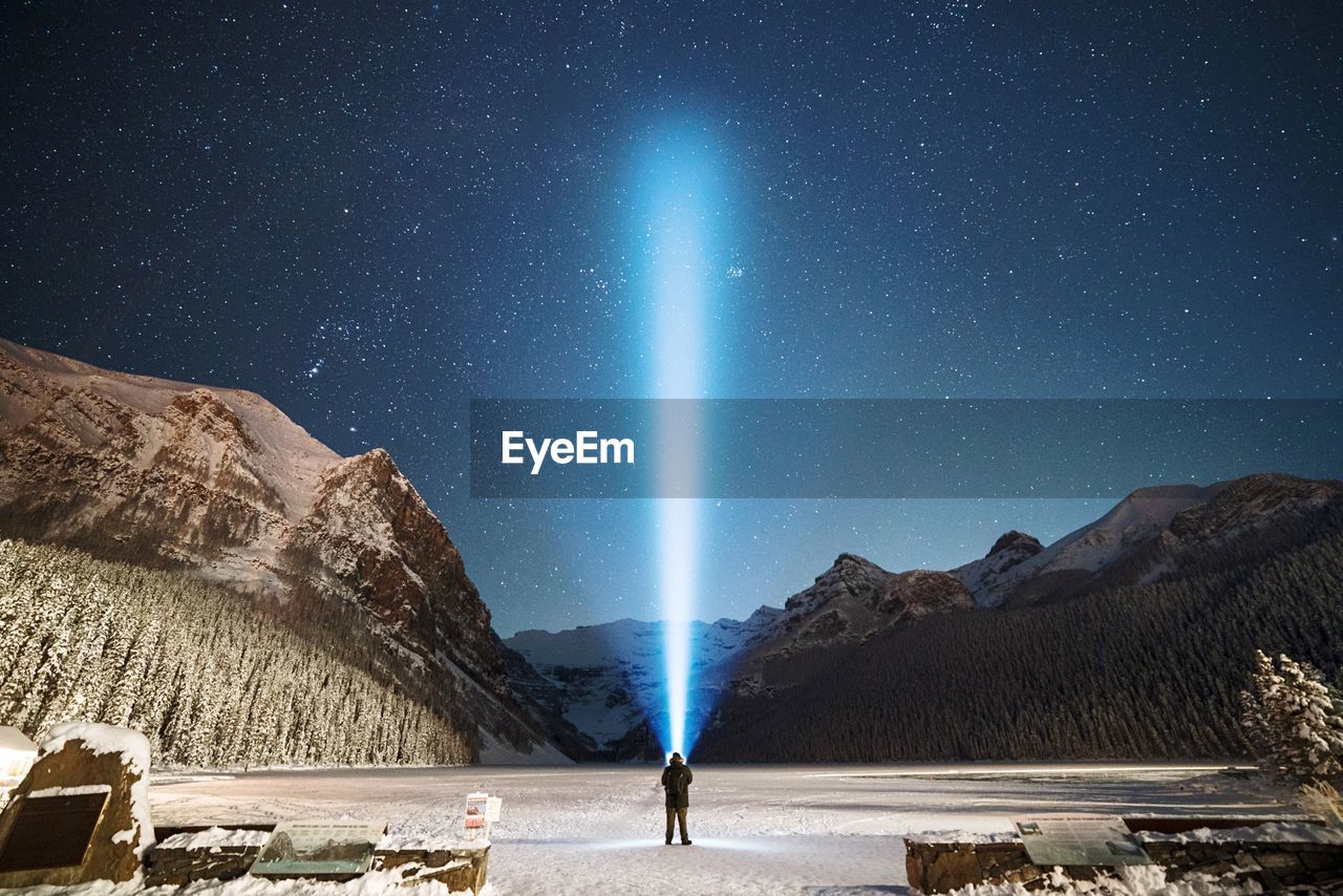 Scenic view of man illuminating sky at night against snow covered landscape