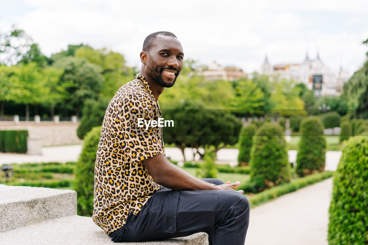 Positive afro american stylish man in european city with electronic device