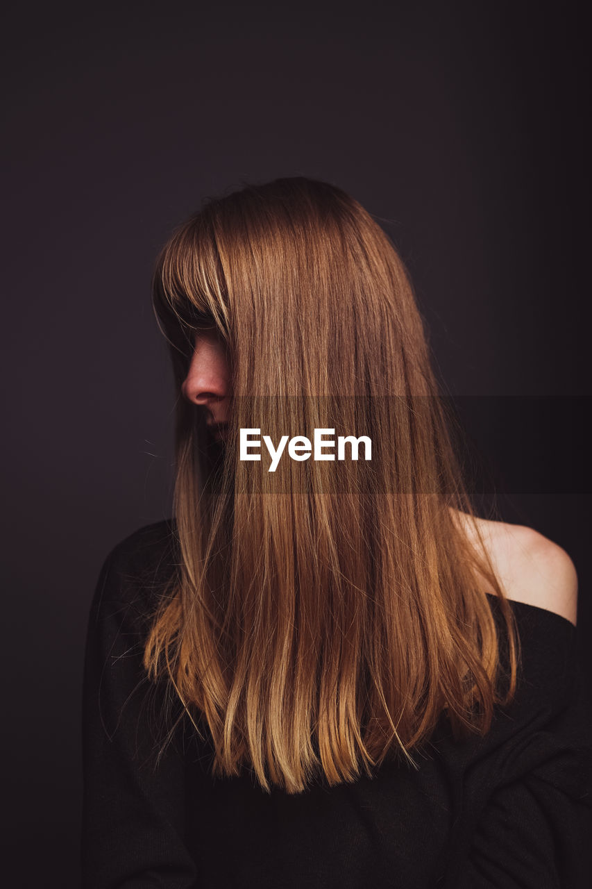 Woman with brown hair against black background