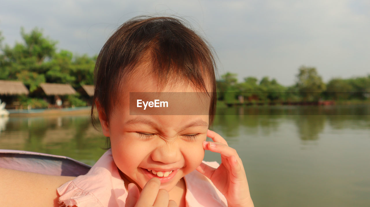 Close-up of laughing girl against lake