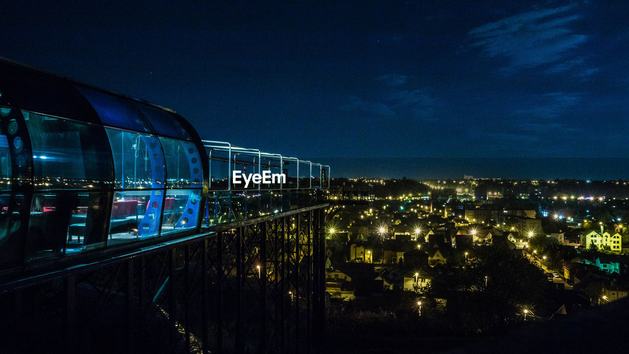 Illuminated cityscape against blue sky at night