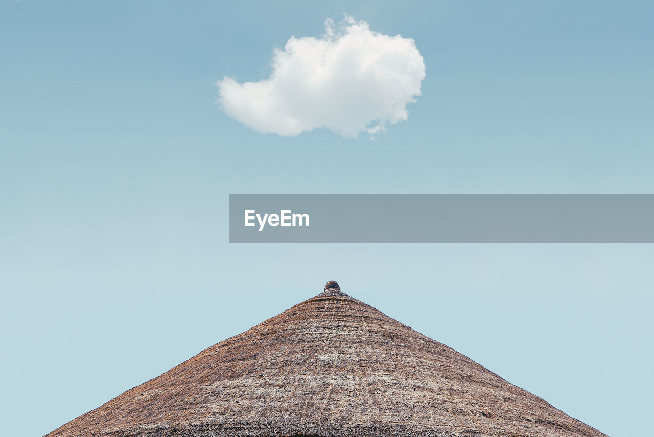 Low angle view of  thatch roof against cloudy sky