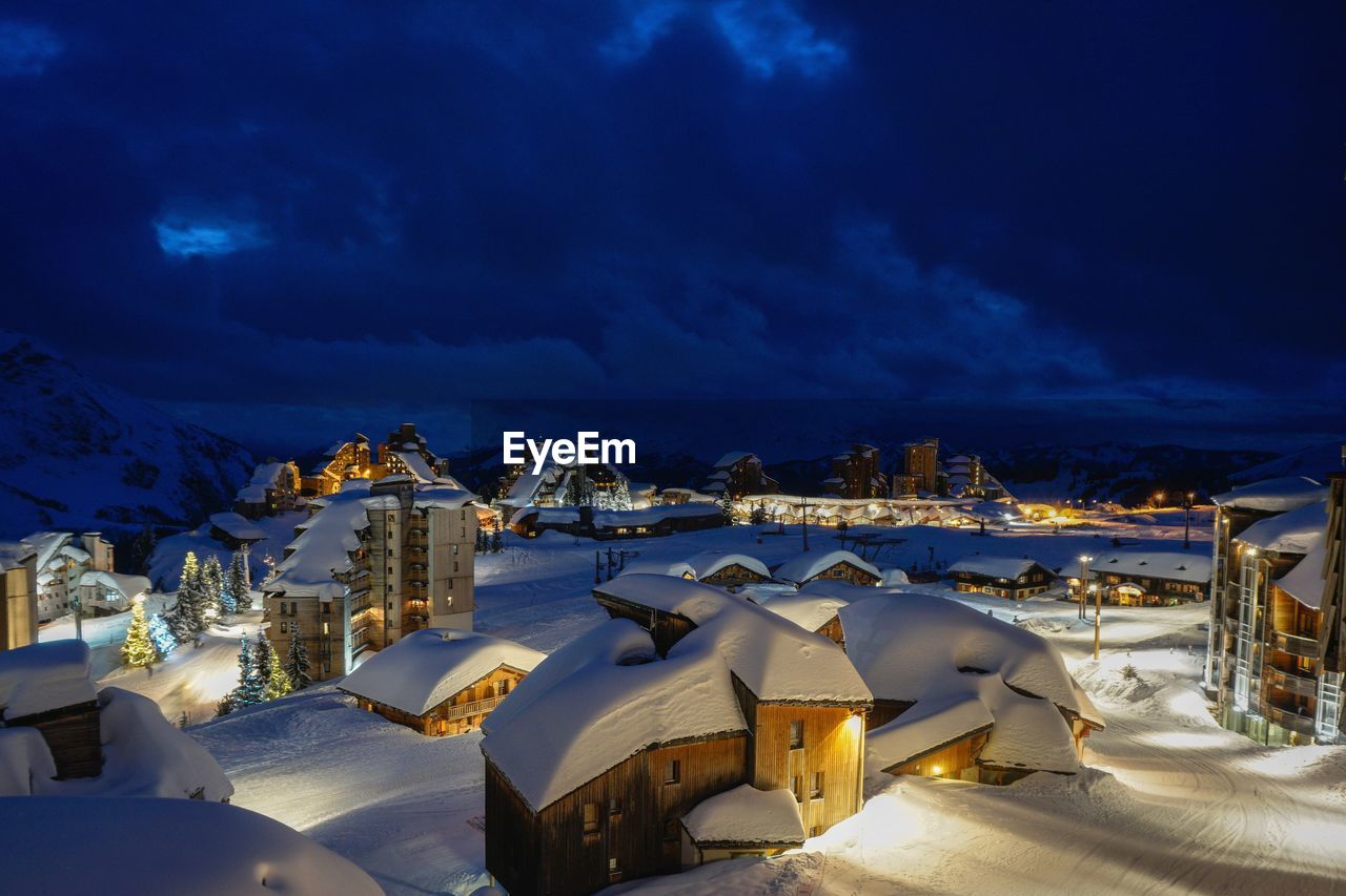 Illuminated buildings against blue sky at night during winter in the mountains