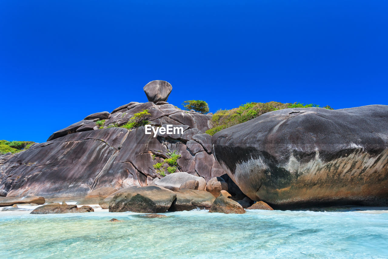 SCENIC VIEW OF ROCK FORMATION IN SEA AGAINST CLEAR BLUE SKY