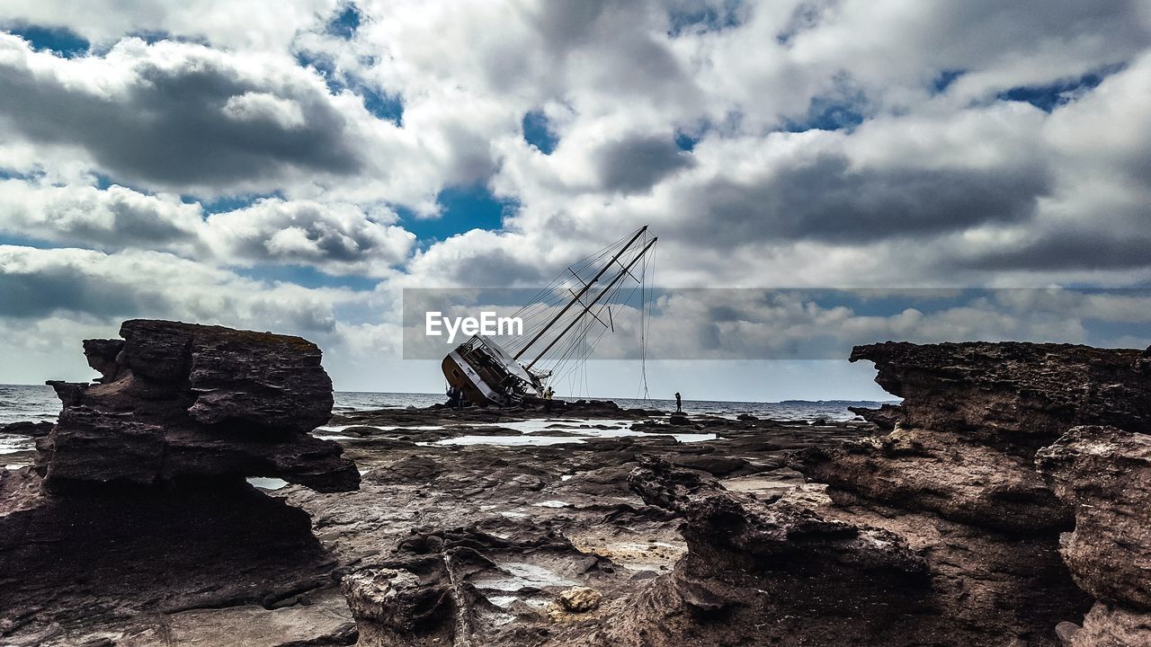 ROCK FORMATIONS ON SHORE AGAINST SKY