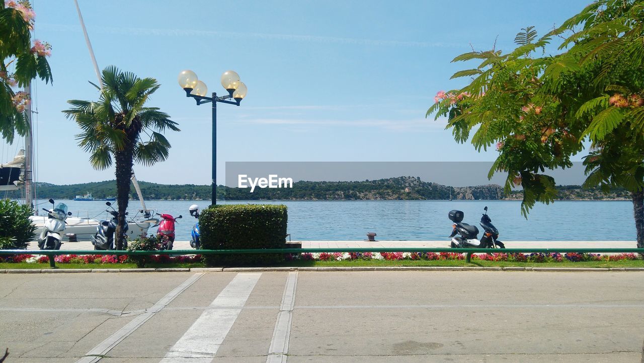 PEOPLE SITTING ON ROAD BY SEA