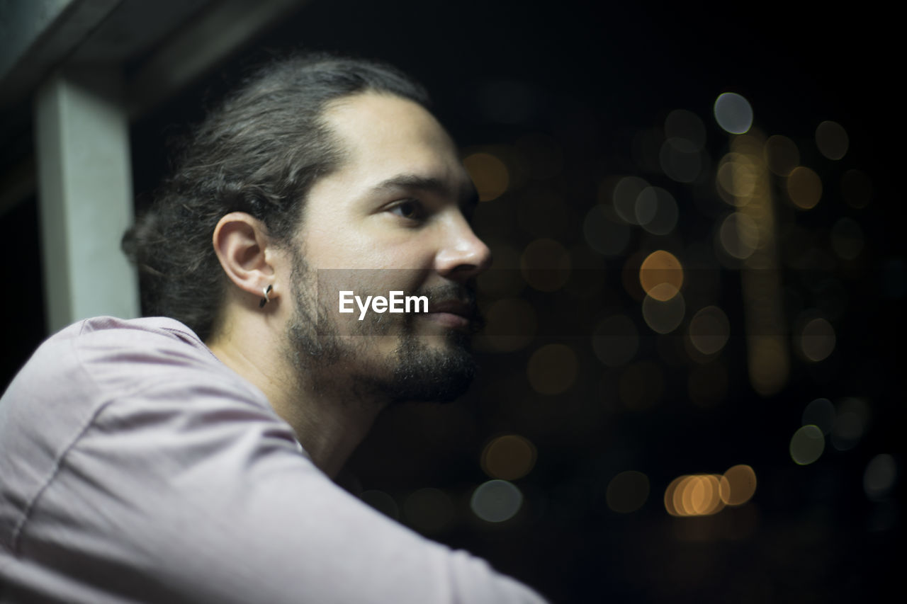 Close-up of thoughtful man looking through window at night