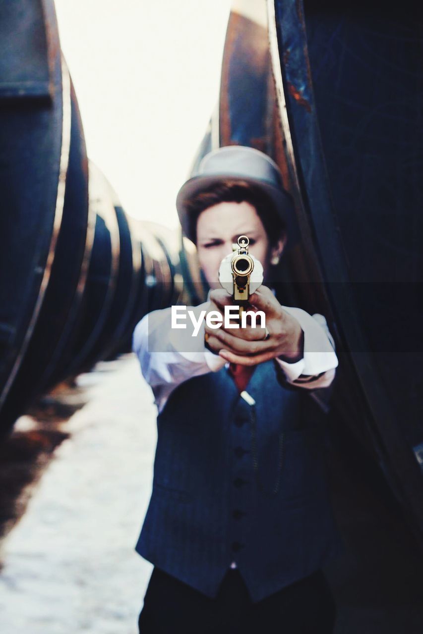 Well-dressed man pointing gun by steam train