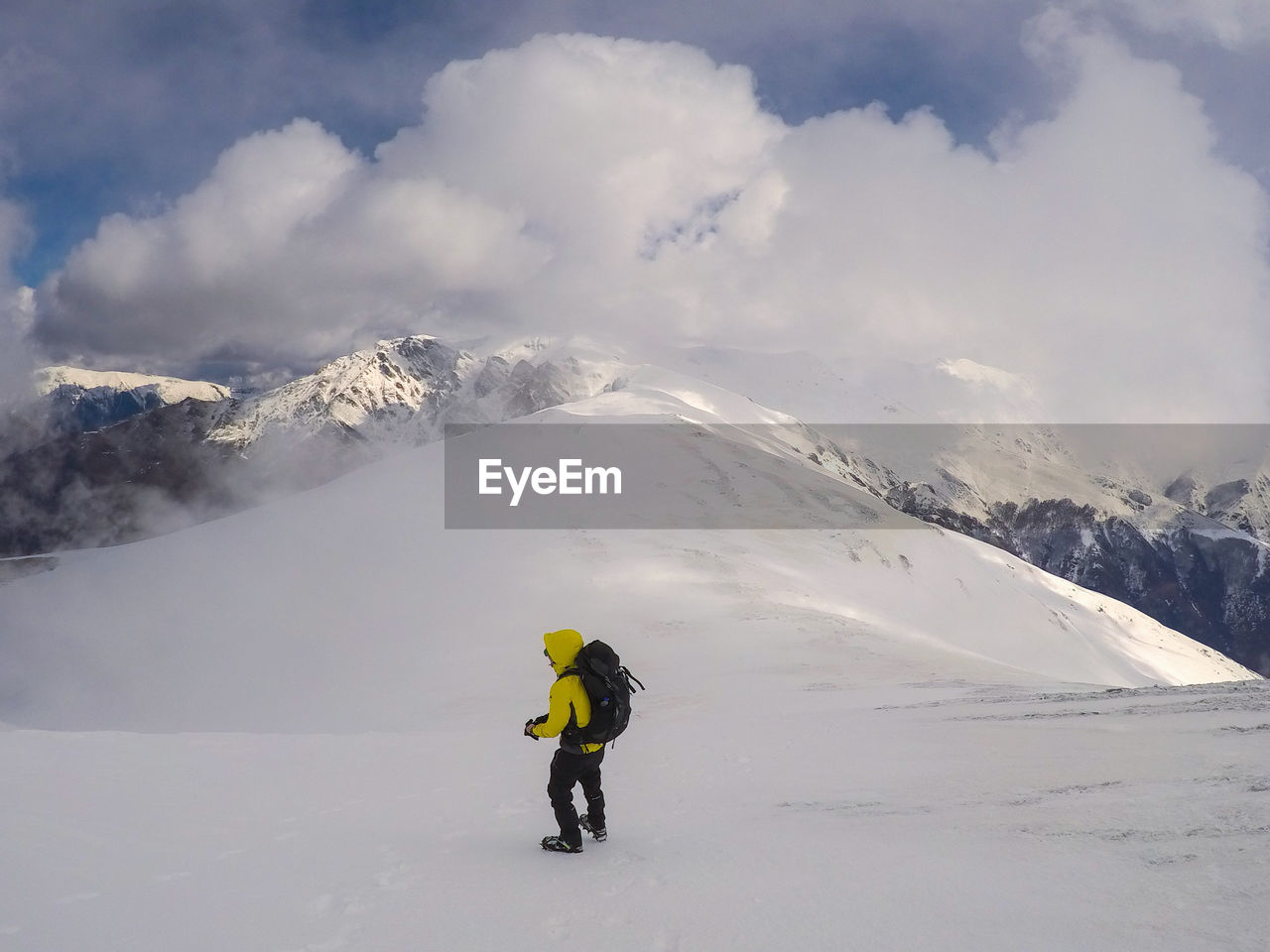 Full length of man on snowcapped mountain against cloudy sky